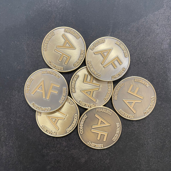 Pile of As F**k Tokens in worn gold color.
