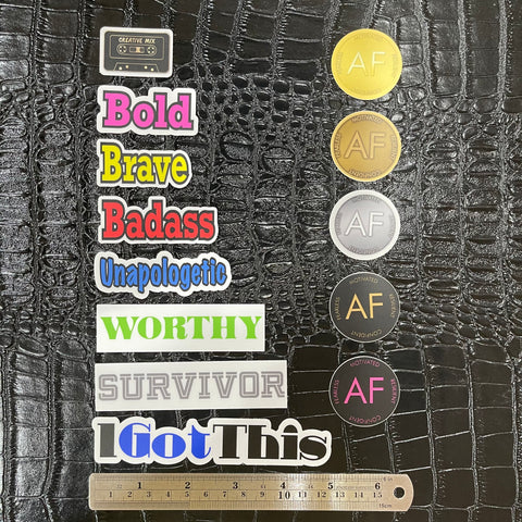 Thirteen vinyl stickers bundle has seven words,  artwork of five of our As F**k Tokens and artwork of our Creative Mix cassette tape enamel pin. A ruler sits under the stickers to help with sizing.
