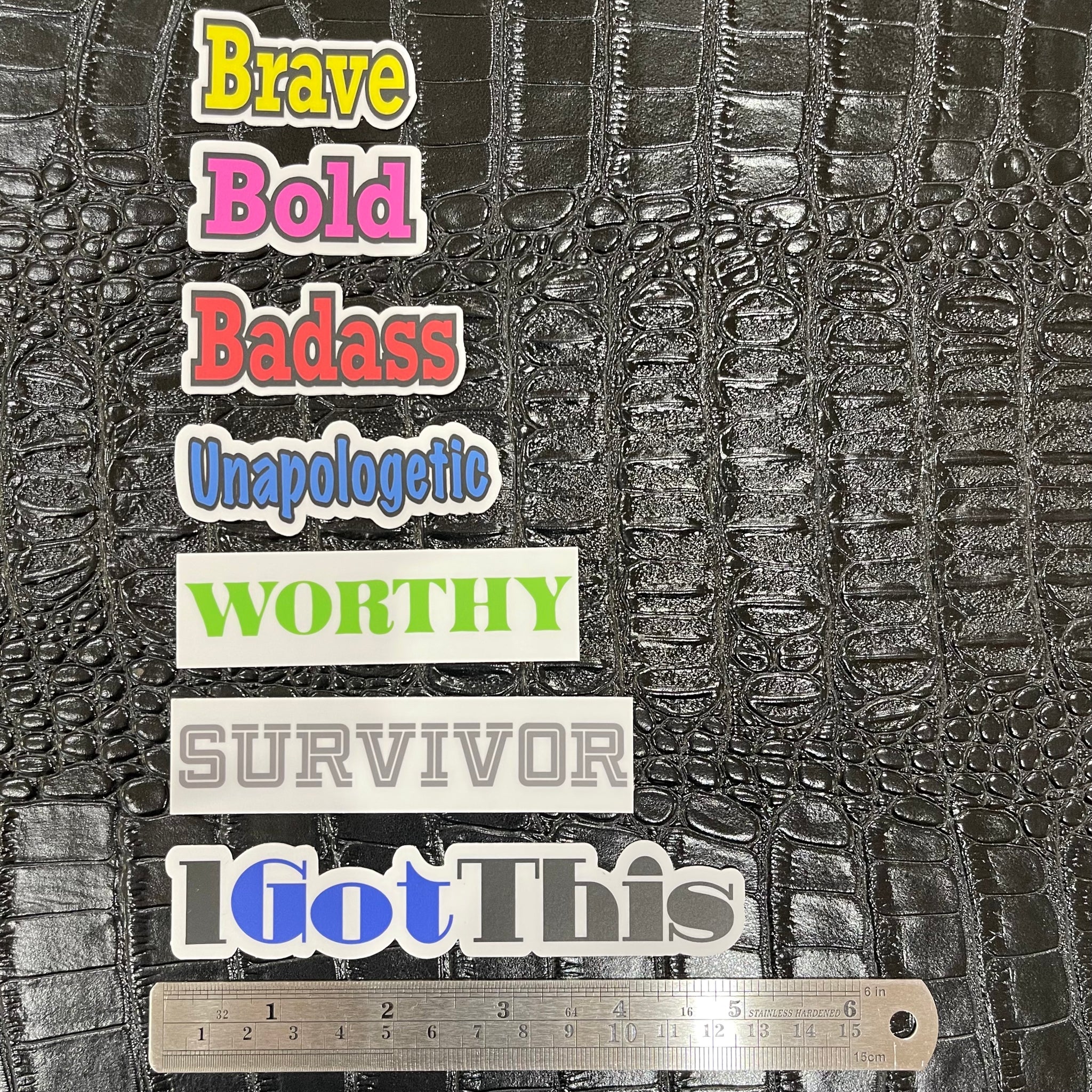 Seven vinyl word stickers. Brave is yellow, Bold is hot pink, Badass is red, Unapologetic is blue, Worthy is neon green, Survivor is gray, I Got This is blue and black.