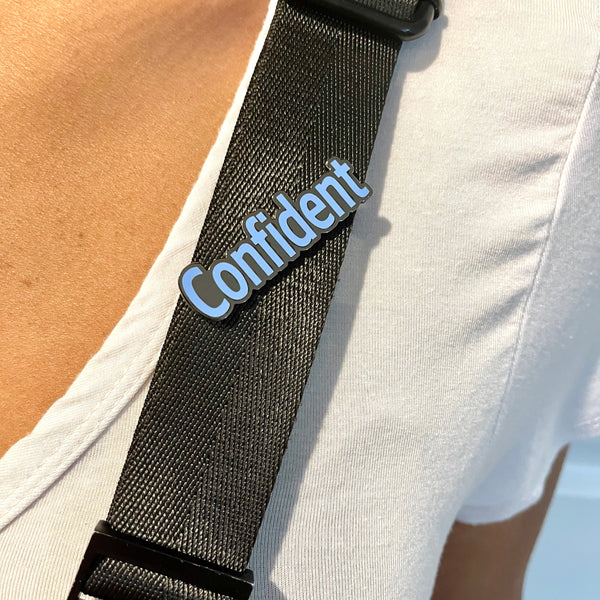 Cornflower blue colored Confident enamel word pin on a purse strap.